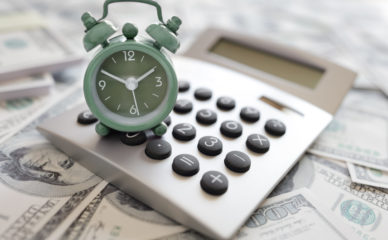 Calculator and alarm clock on money concept for time is money or tax and savings deadline